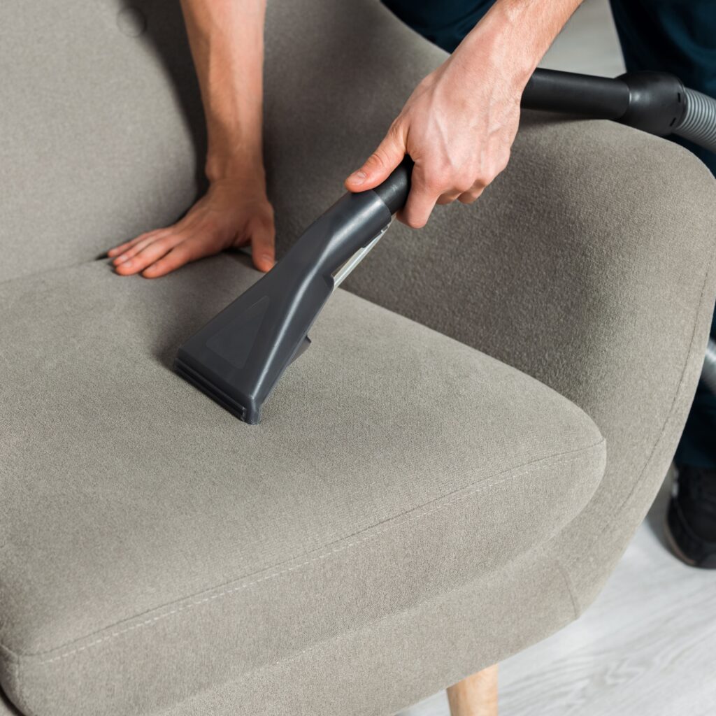 cropped view of cleaner washing armchair with vacuum in living room